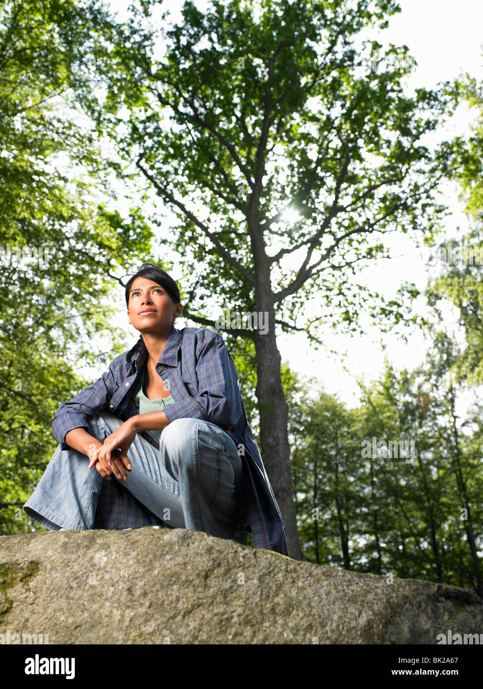 Frau sitzt auf einem Felsen im Wald Stockfoto