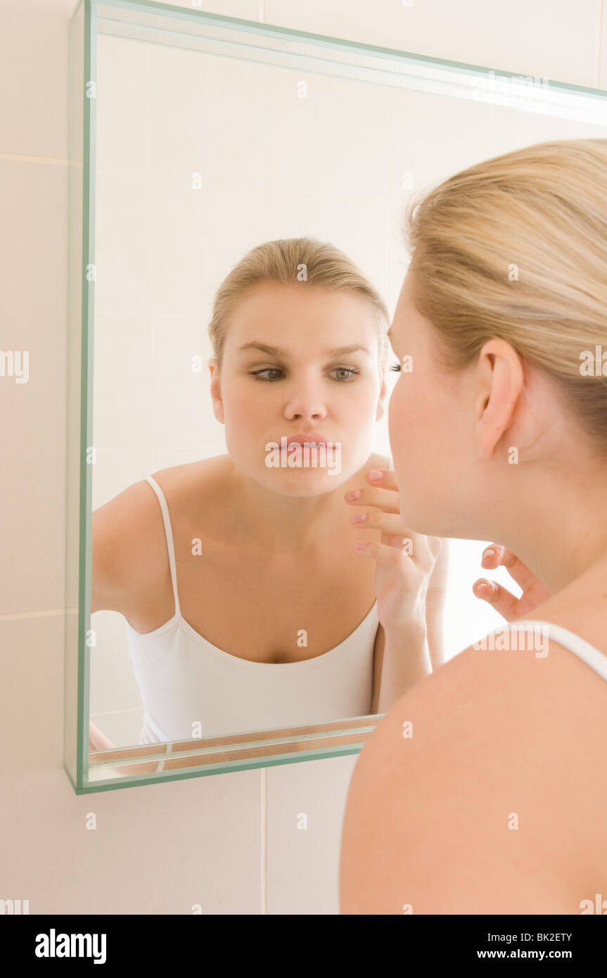 Weibliche Schönheit, Inspektion der Haut im Spiegel Stockfoto