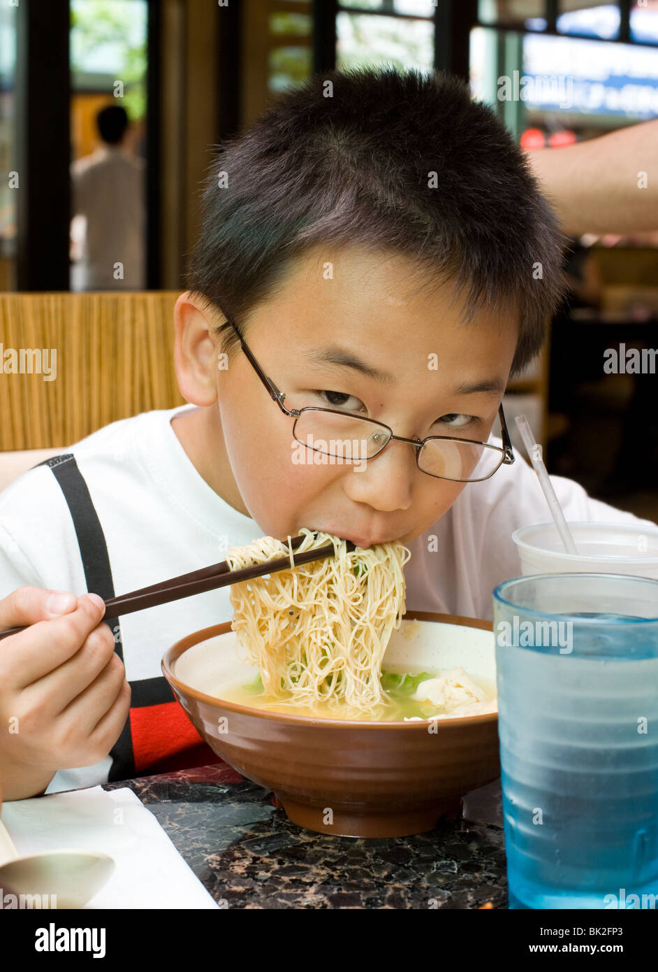 Chinesischen jungen Essen Ramen-Nudeln und Garnelen-Wan-Tan-Suppe mit Stäbchen im Chi-Cafe in Chicago, Illinois Stockfoto