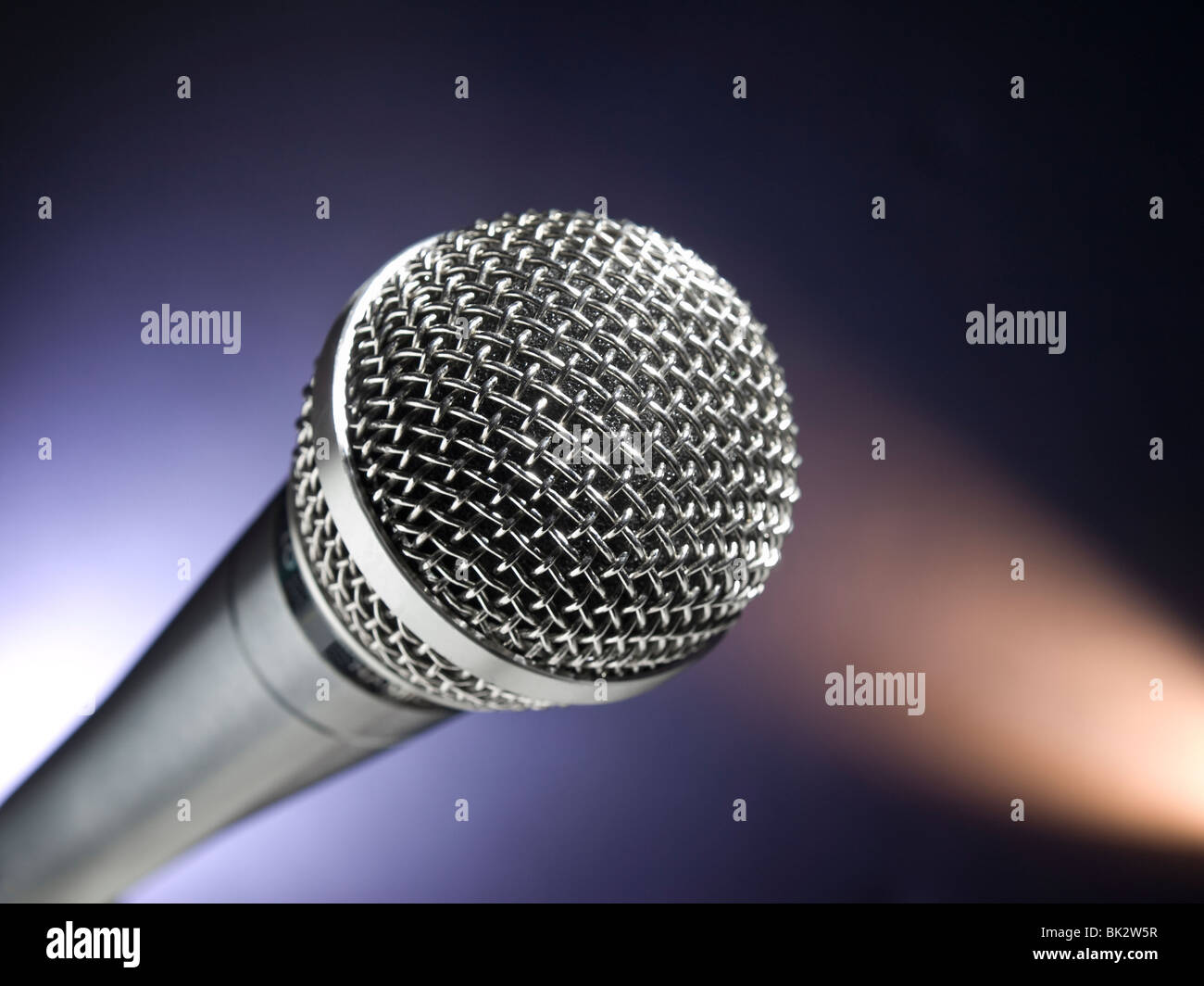 Ein dynamisches Mikrofon auf der Bühne. Farbe Scheinwerfer als Hintergrund. Stockfoto