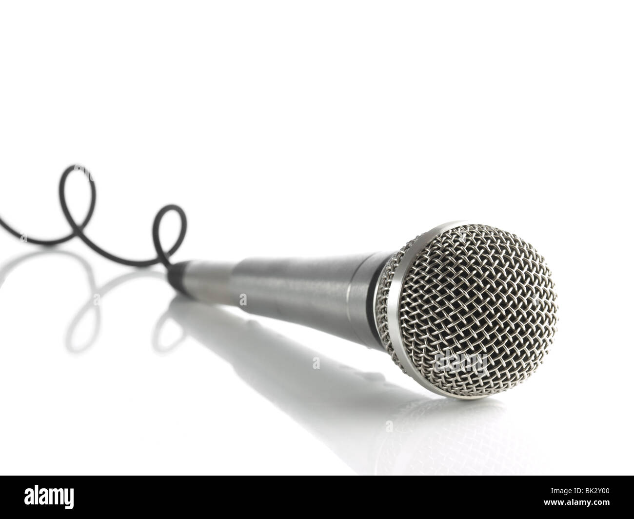 Ein dynamisches Mikrofon mit einem gekräuselten Kabel über weiß. Stockfoto
