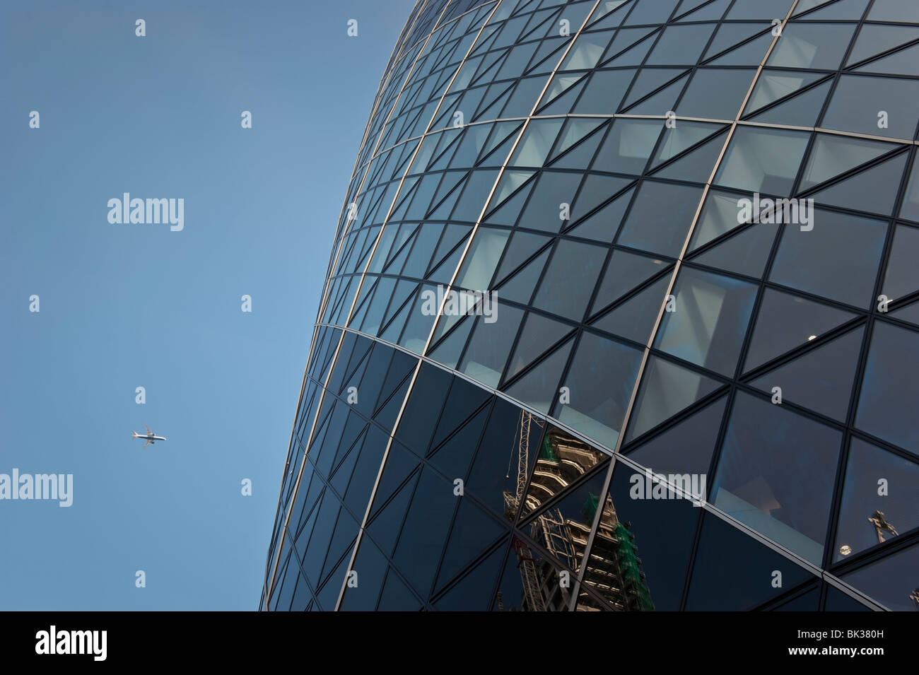 Betrachtet von unten mit einem Flugzeug am Himmel über London Gherkin-Turm. Stockfoto