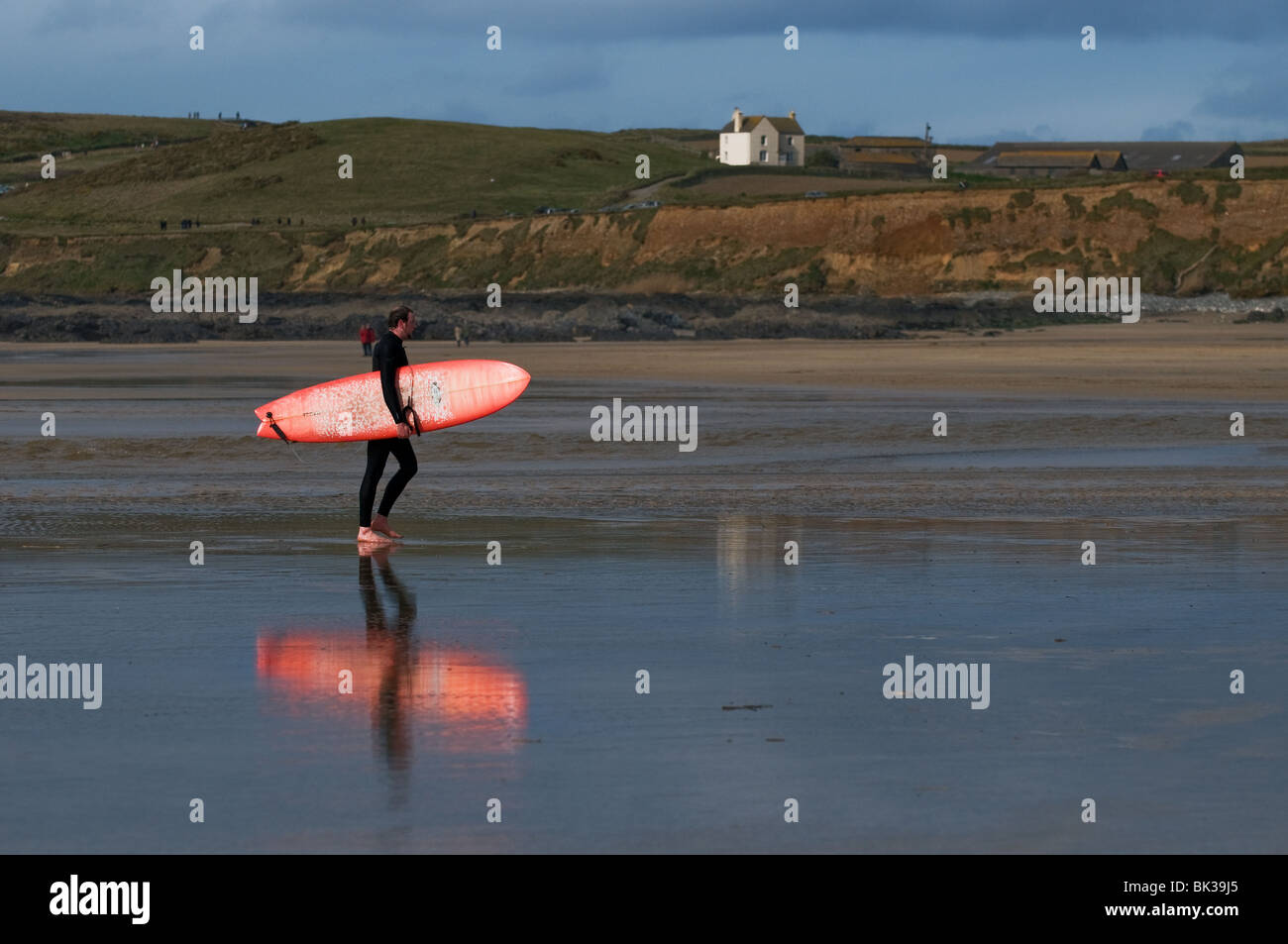 Ein Surfer entlang Gwithian Towans Strand in Cornwall. Stockfoto