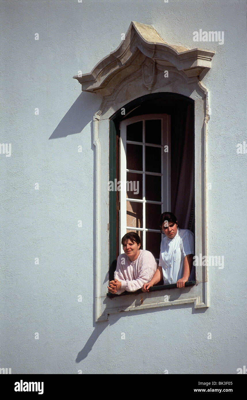 Zwei Personen blicken aus dem Fenster eines privaten Hause, Portugal Stockfoto