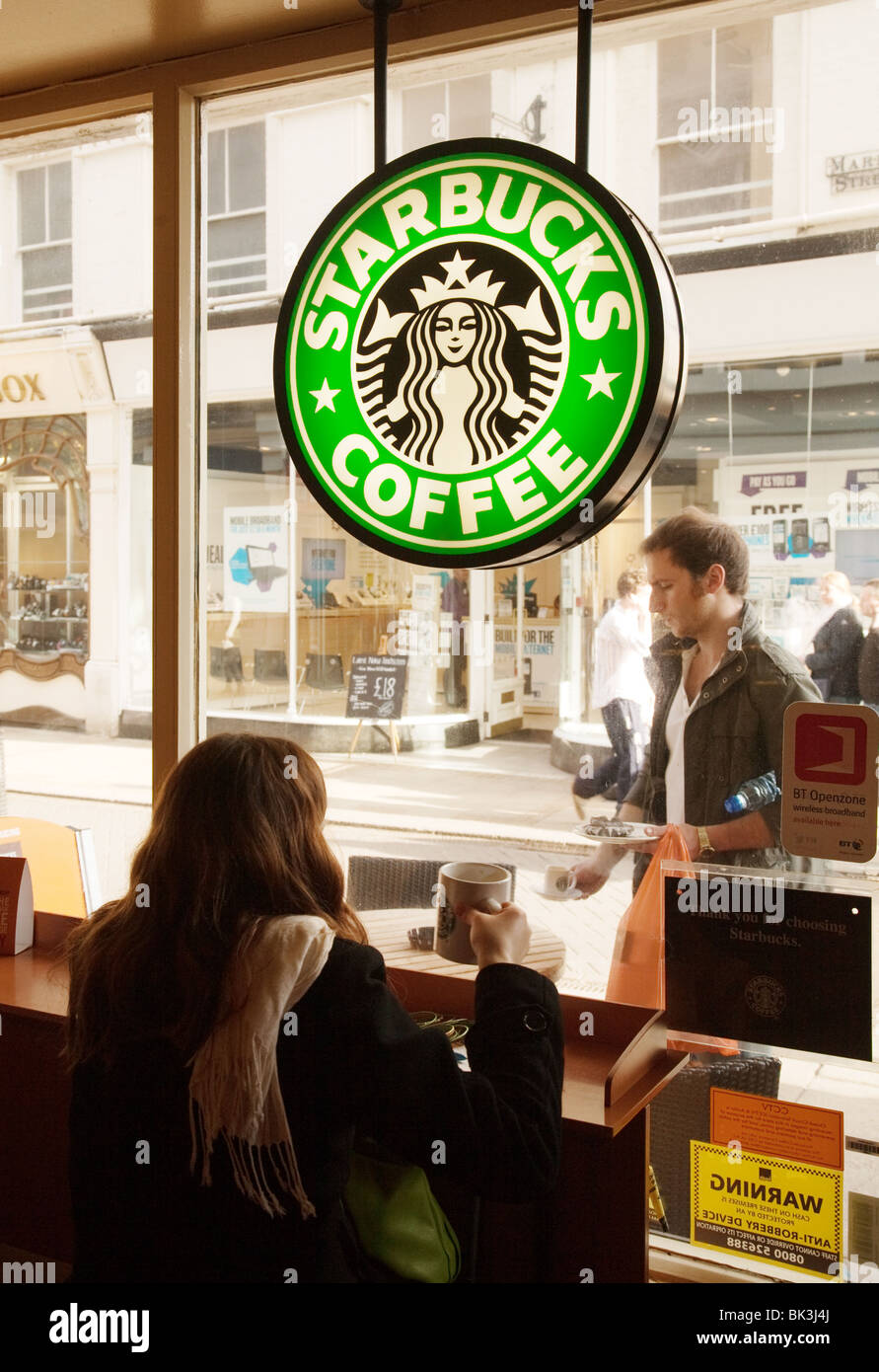 Ein Mädchen sitzt im Fenster der Starbucks Kaffee trinken, Cambridge, UK Stockfoto
