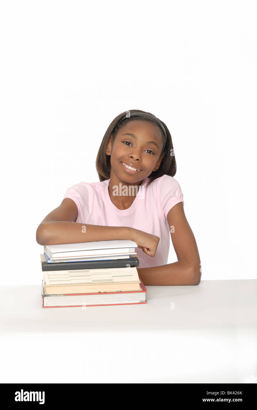 Zehn Jahre altes Mädchen lächelnd und stützte sich auf einen Stapel Bücher. Stockfoto