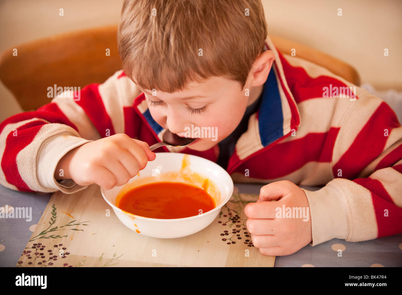 Ein MODEL Release Bild eines sechsjährigen Jungen essen eine Schale mit Tomatensuppe zu Hause im Vereinigten Königreich Stockfoto