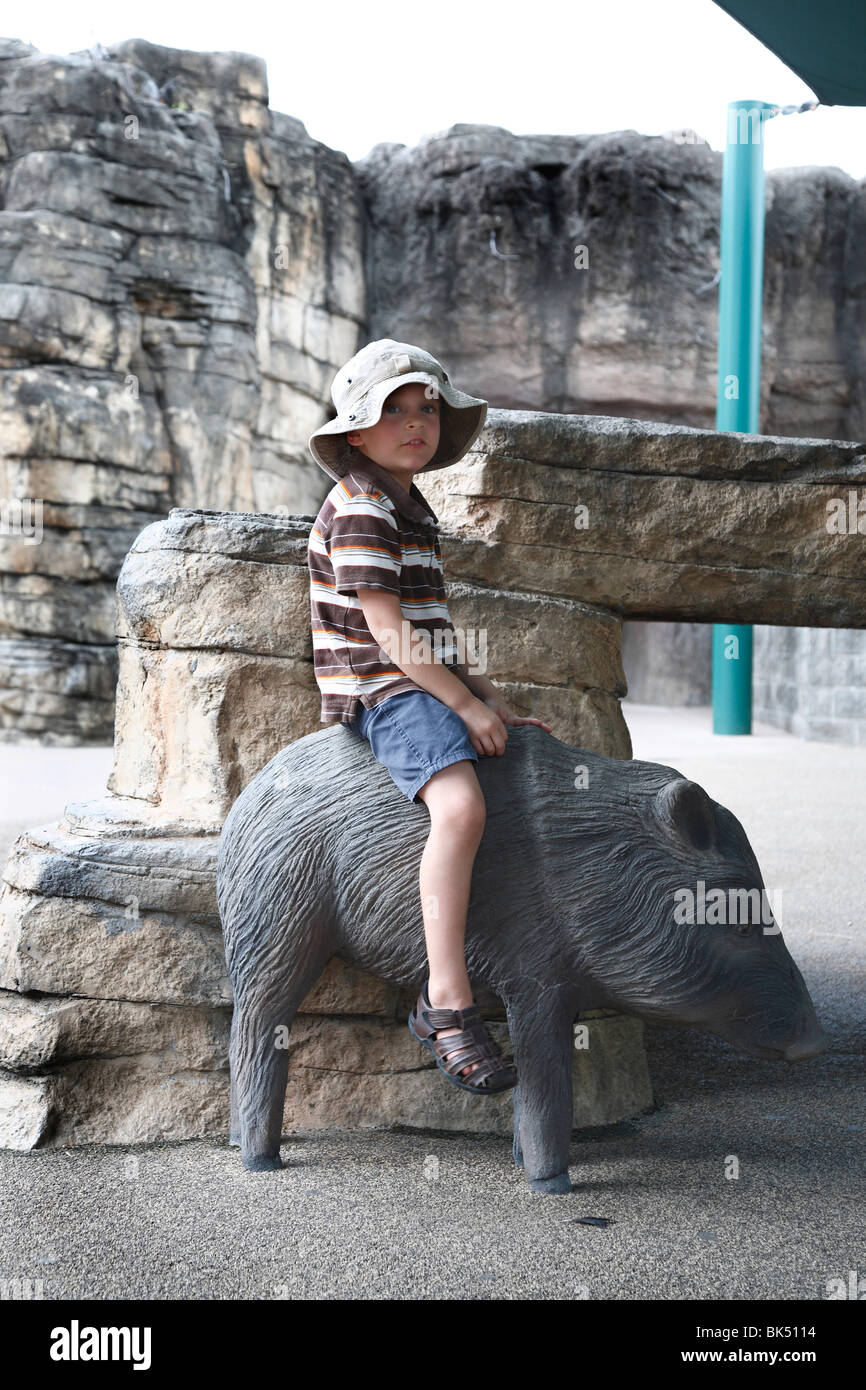 Junge sitzt auf der Statue des Ebers Stockfoto