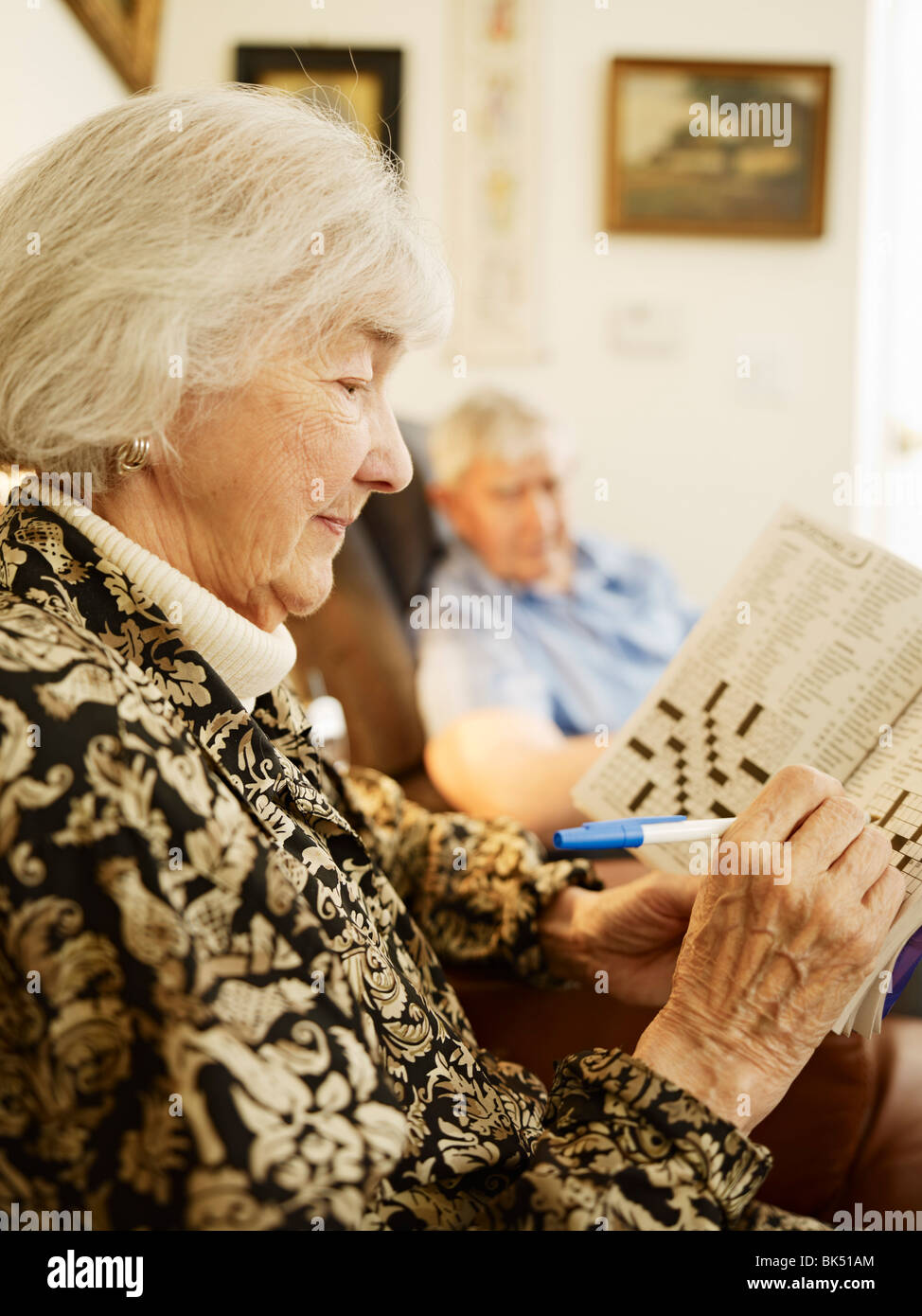Älteres Ehepaar im Seniorenheim, Frau arbeitet auf Kreuzworträtsel Stockfoto