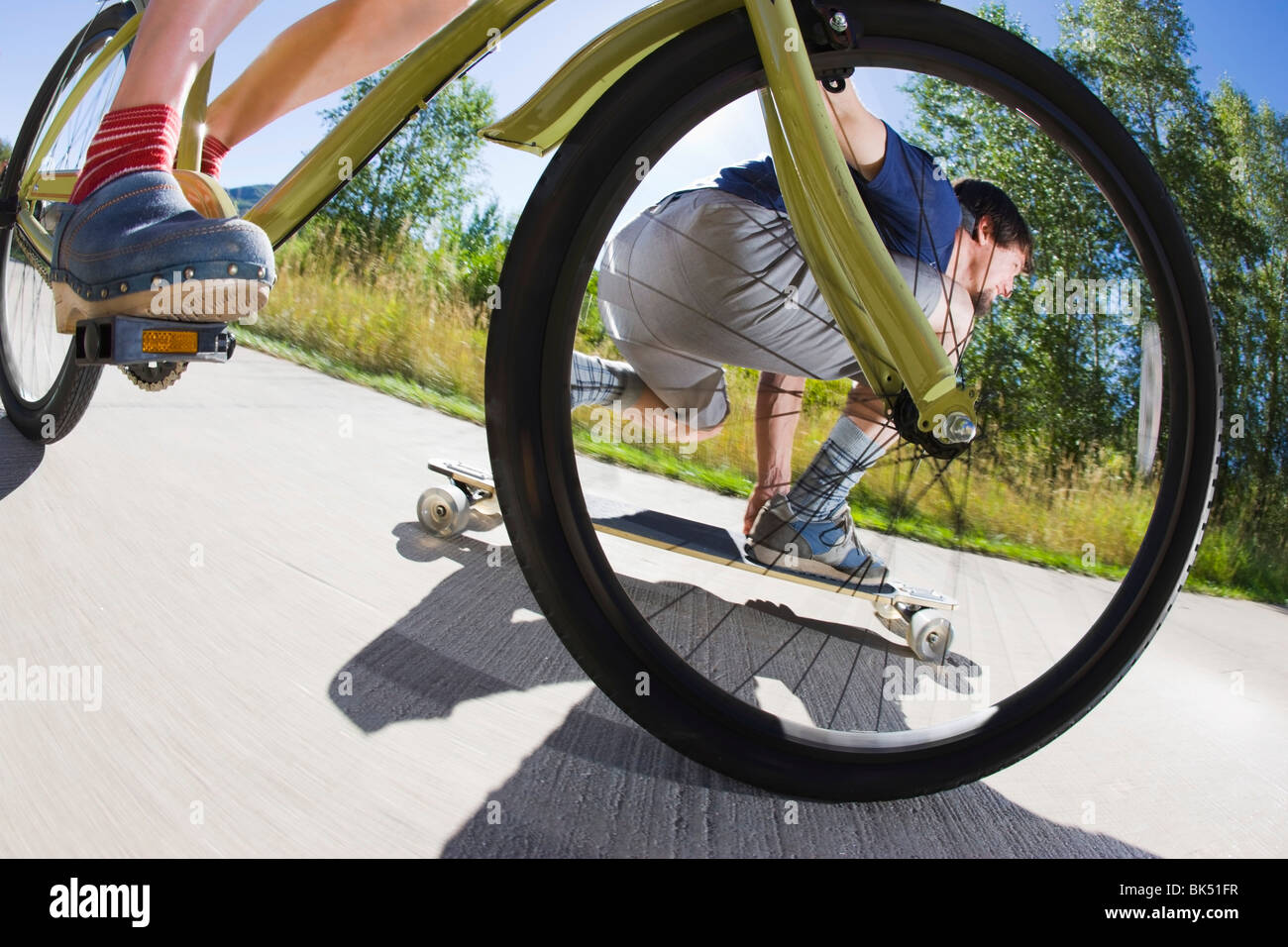 Frau auf dem Fahrrad und Mann reitet eine Skateboard auf ein Fahrrad Weg, Steamboat Springs, Routt County, Colorado, USA Stockfoto