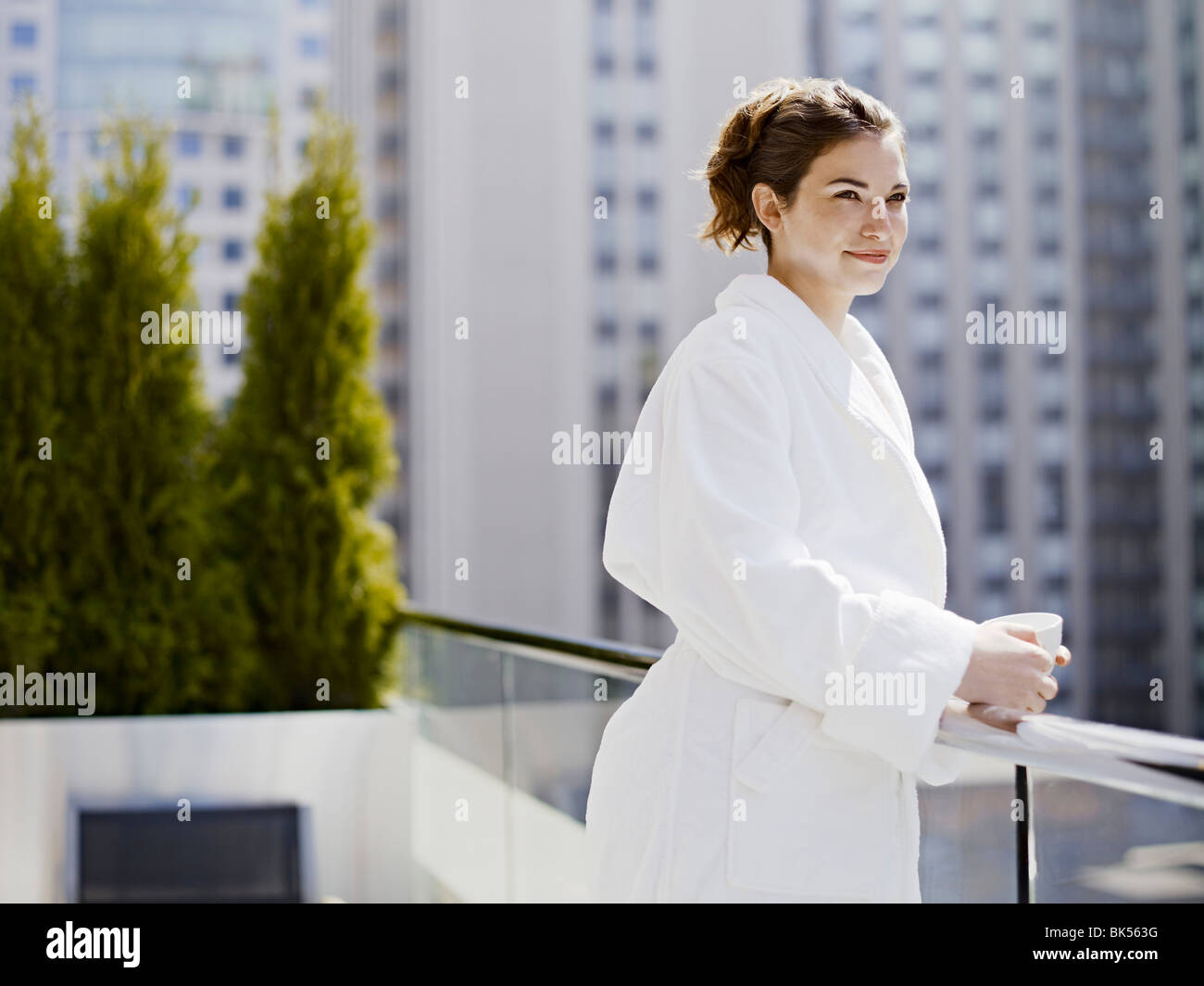 Frau im Bademantel auf dem Balkon stehend Stockfoto