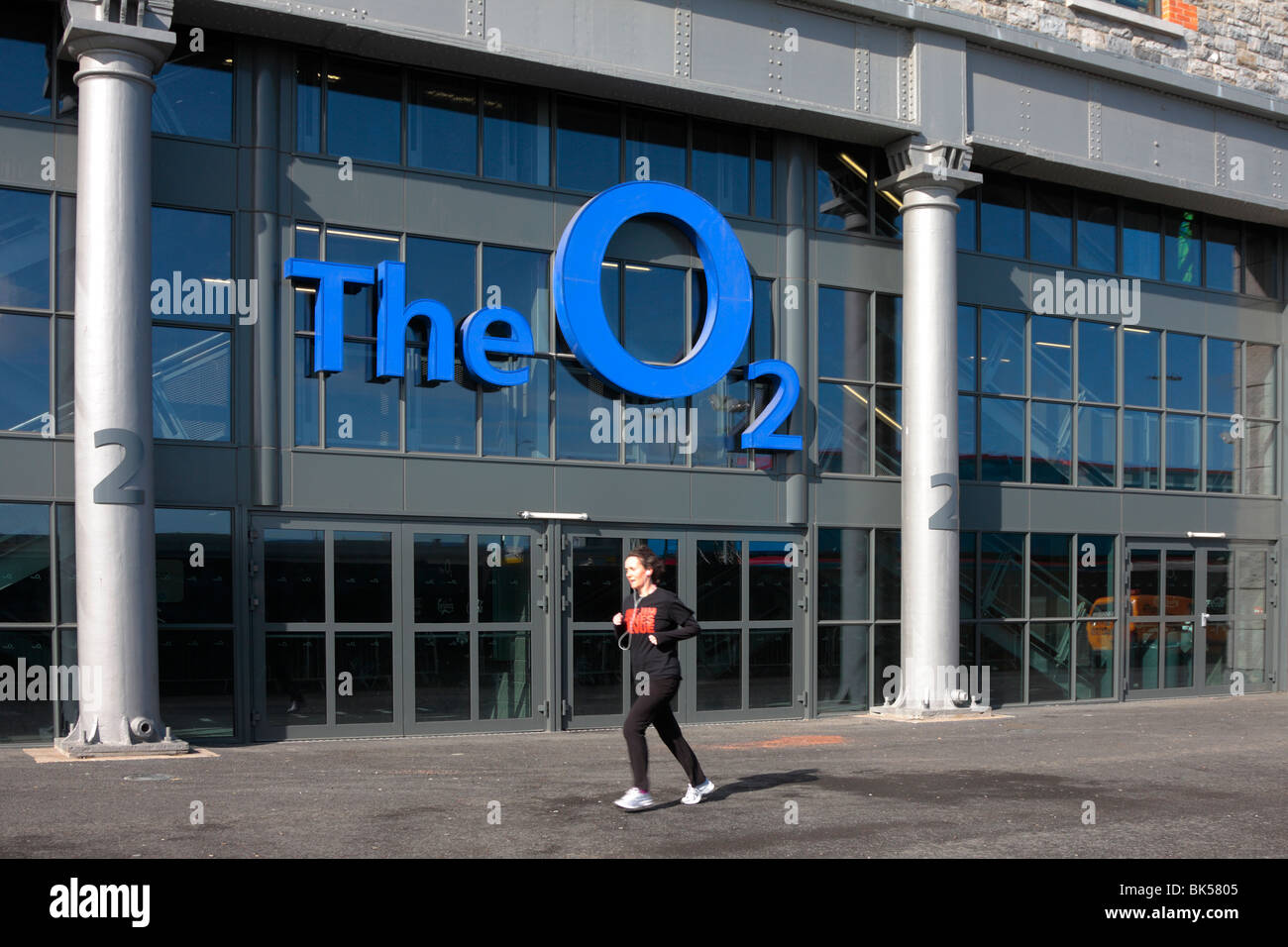 Eine Frau joggt vorbei an der Tür des komplexen The O2 in Dublin Veranstaltungsort für Konzerte und shows früher bekannt als der Punkt Dublin Irland Stockfoto