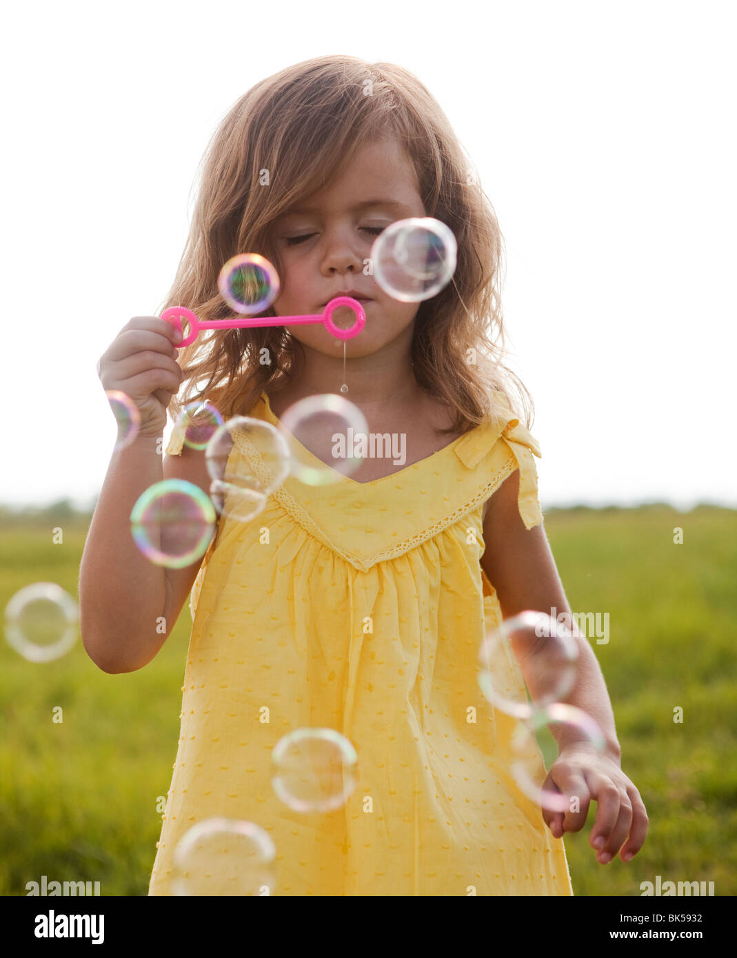 Junges Mädchen im gelben Sommerkleid, Seifenblasen Stockfoto