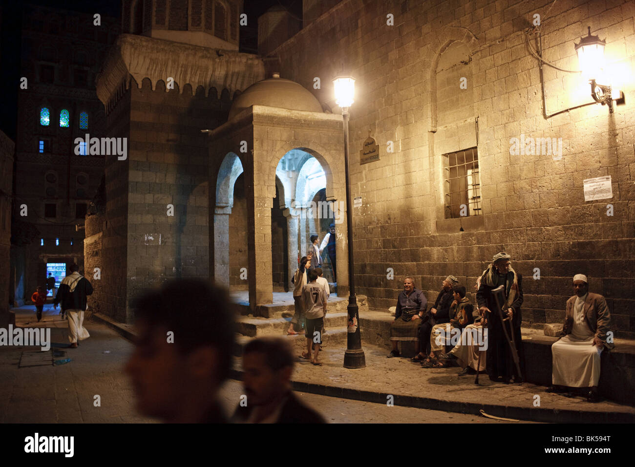 Menschen in der Nacht vor einer alten Moschee in Sanaa, Jemen Stockfoto