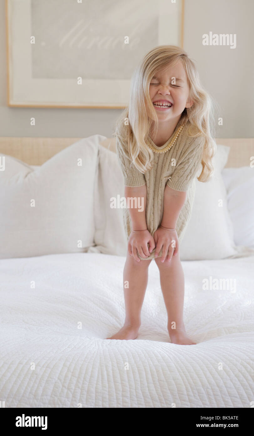 Mädchen mit großen Lächeln stehen auf Bett Stockfoto
