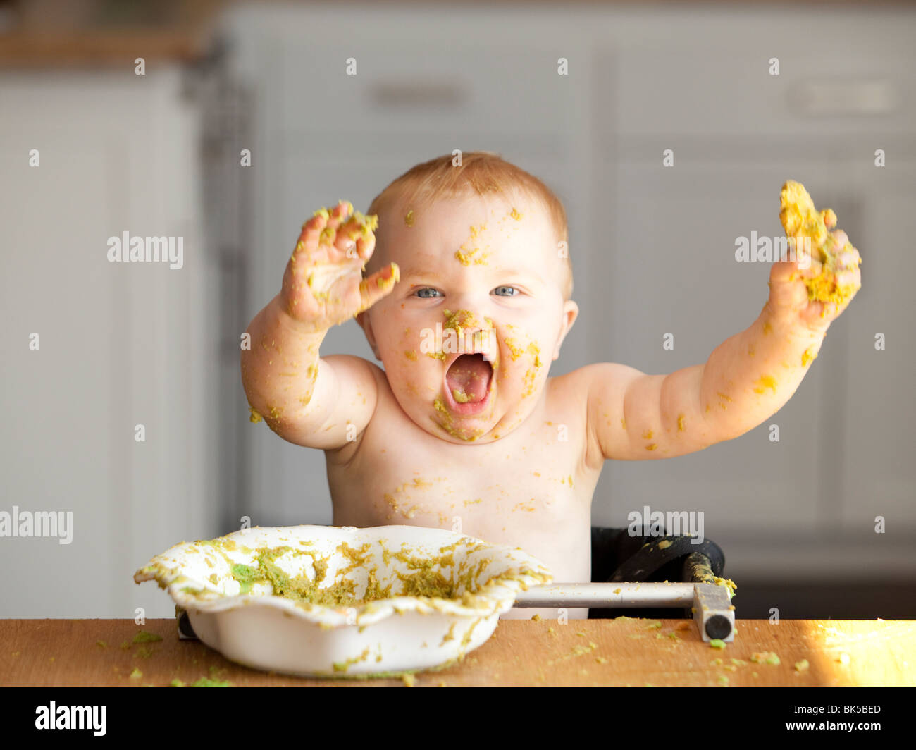 Glückliches Baby spielen in Schüssel mit Erbsen Stockfoto