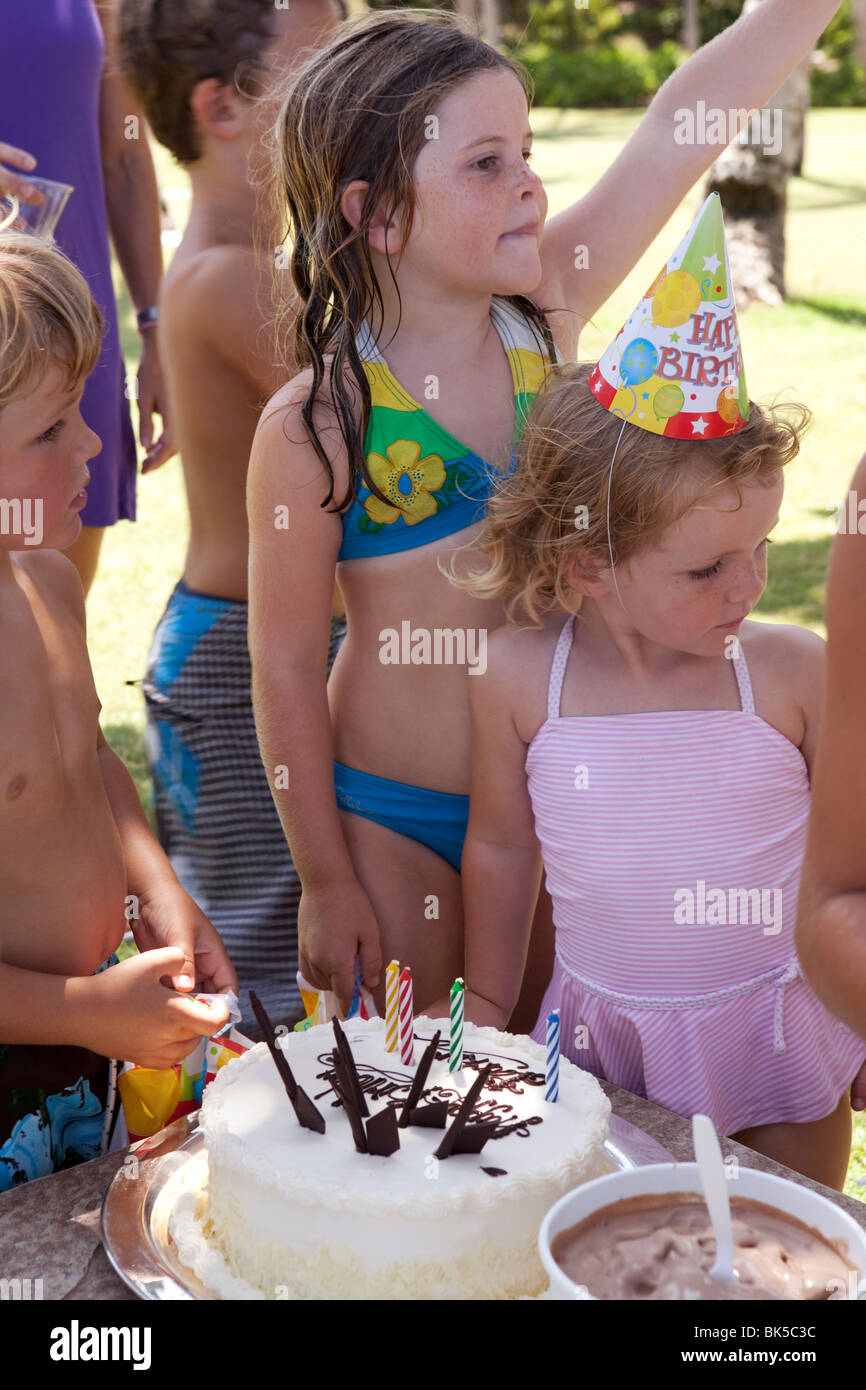 Kinder in Badeanzügen um Geburtstagskuchen Stockfoto