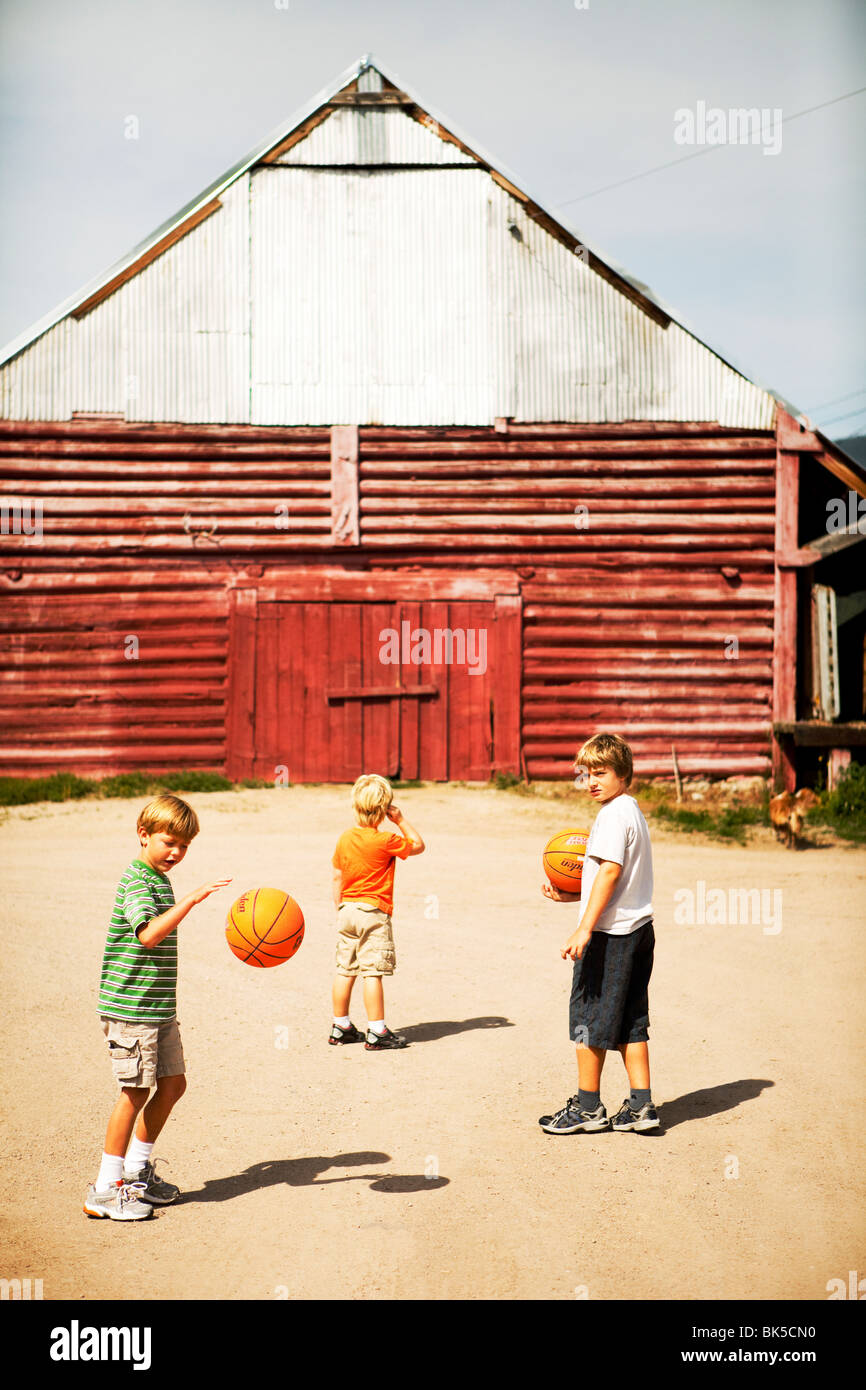 Jungen spielen Basketball in der Nähe von Scheune Stockfoto