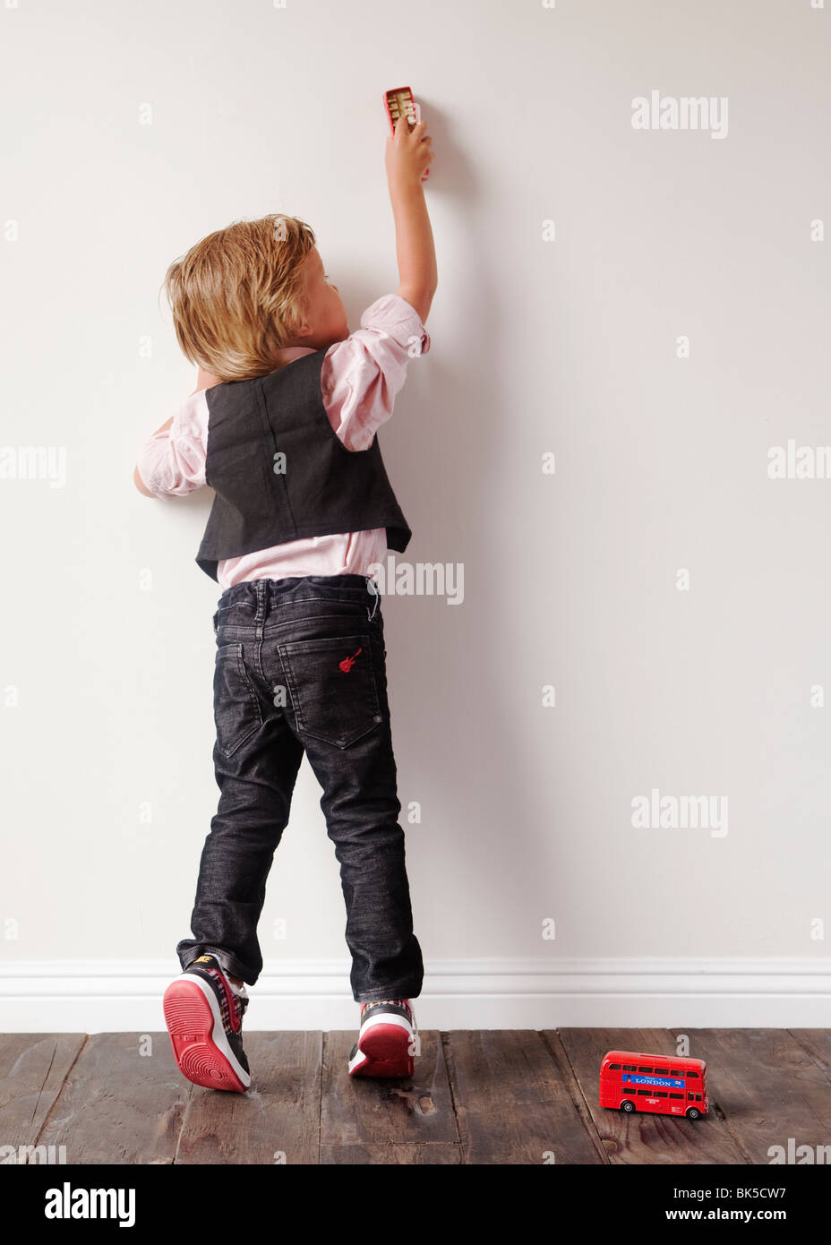 Kleiner Junge spielt mit Spielzeugautos auf Wand Stockfoto