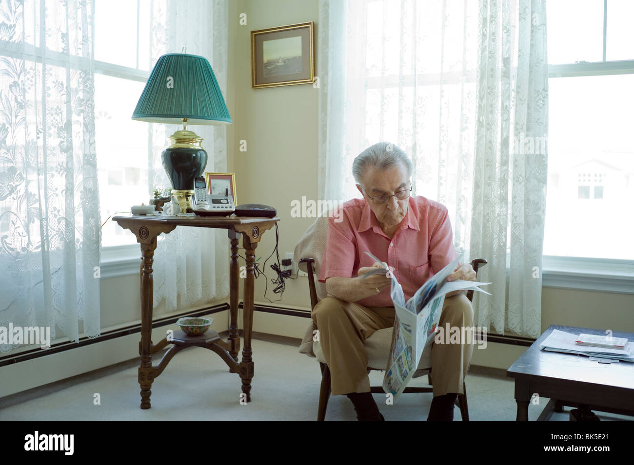 Breite Schuss von älterer Mann sitzt im Stuhl und Las Zeitung. Stockfoto