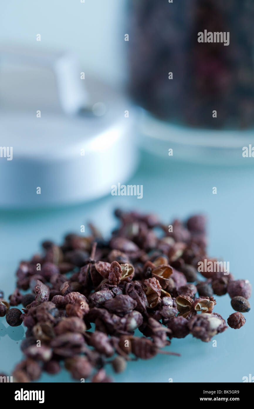 Szechuan Pfefferkörner in einem kleinen Stapel auf einen Glastisch mit dem jar Unscharf im Hintergrund, Lebensmittel, Spice Stockfoto