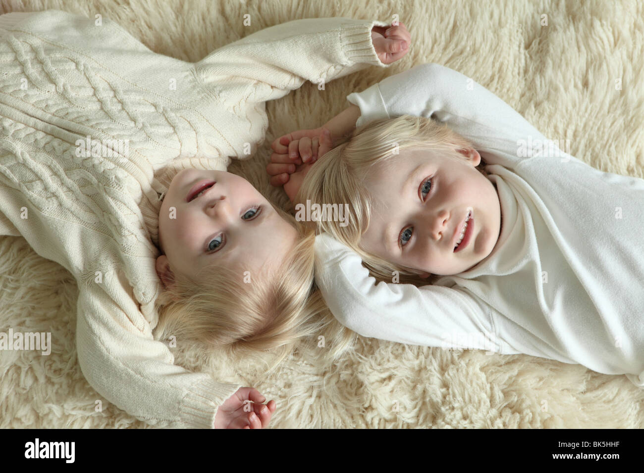 Bruder und Schwester auf Schaffell Teppich Verlegen Stockfoto