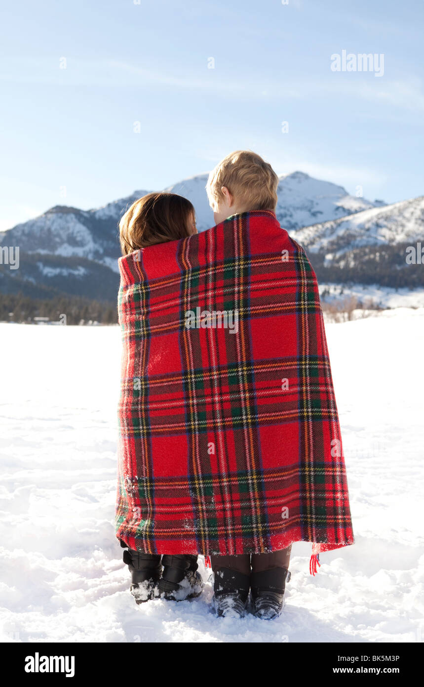 Jungen und Mädchen in rot karierten Decke im Schnee gewickelt Stockfoto