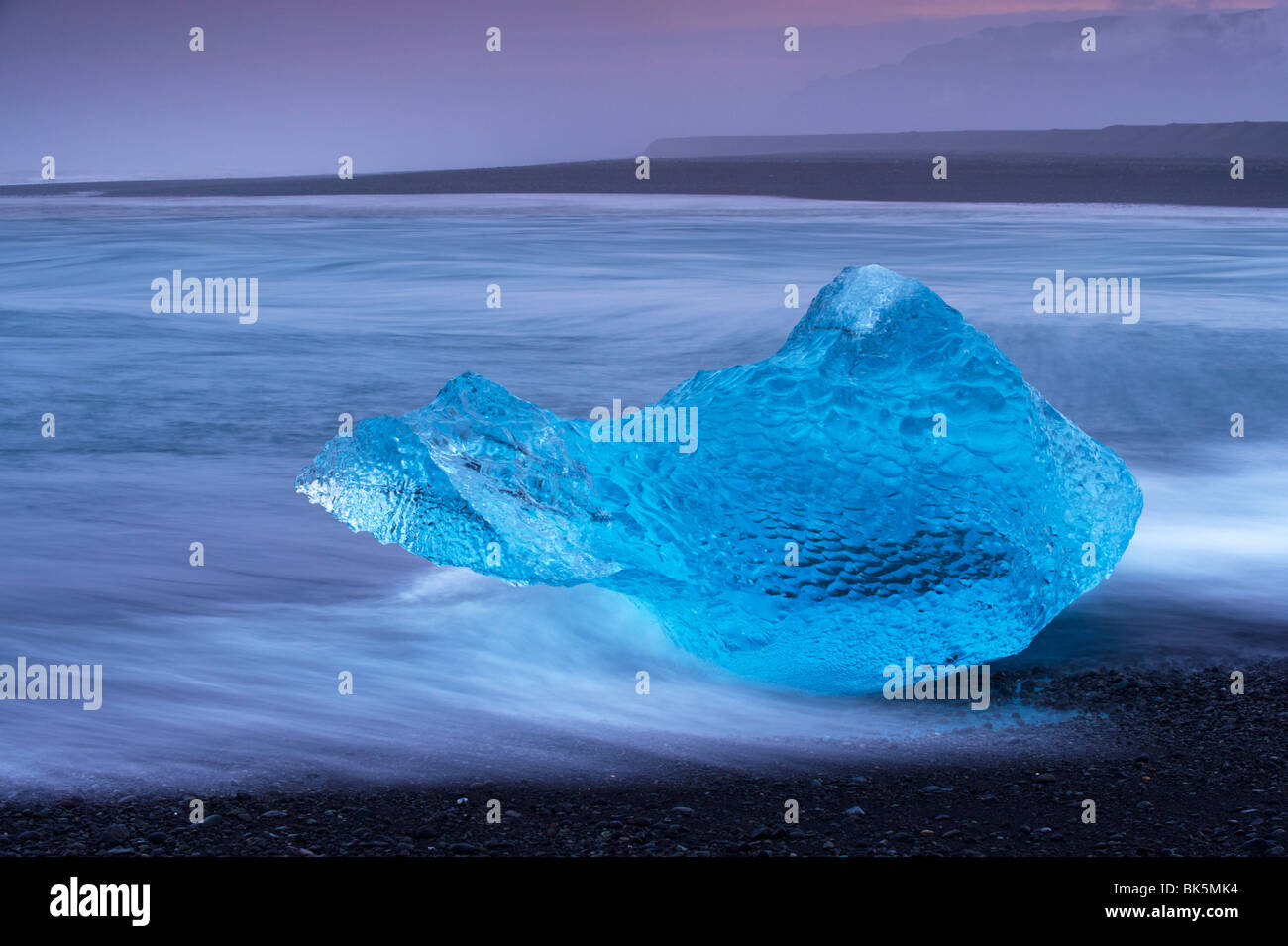 Transluzent blau Eisberg wusch an Land auf Breidamerkursandur schwarzen Sand, in der Nähe Gletscherlagune Jökulsárlón, Ostisland Stockfoto