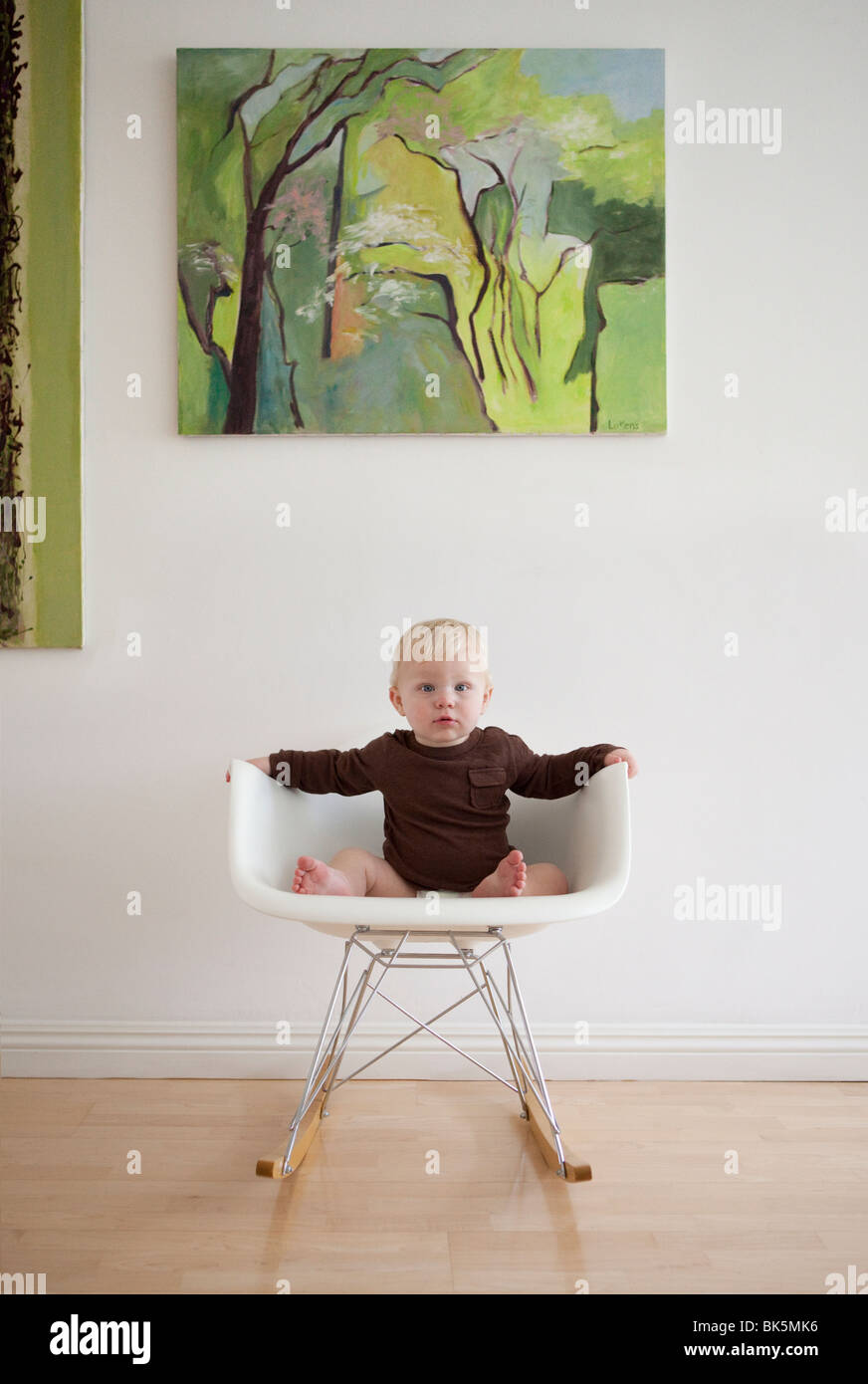 Baby im braunen Hemd auf modernen Schaukelstuhl Stockfoto