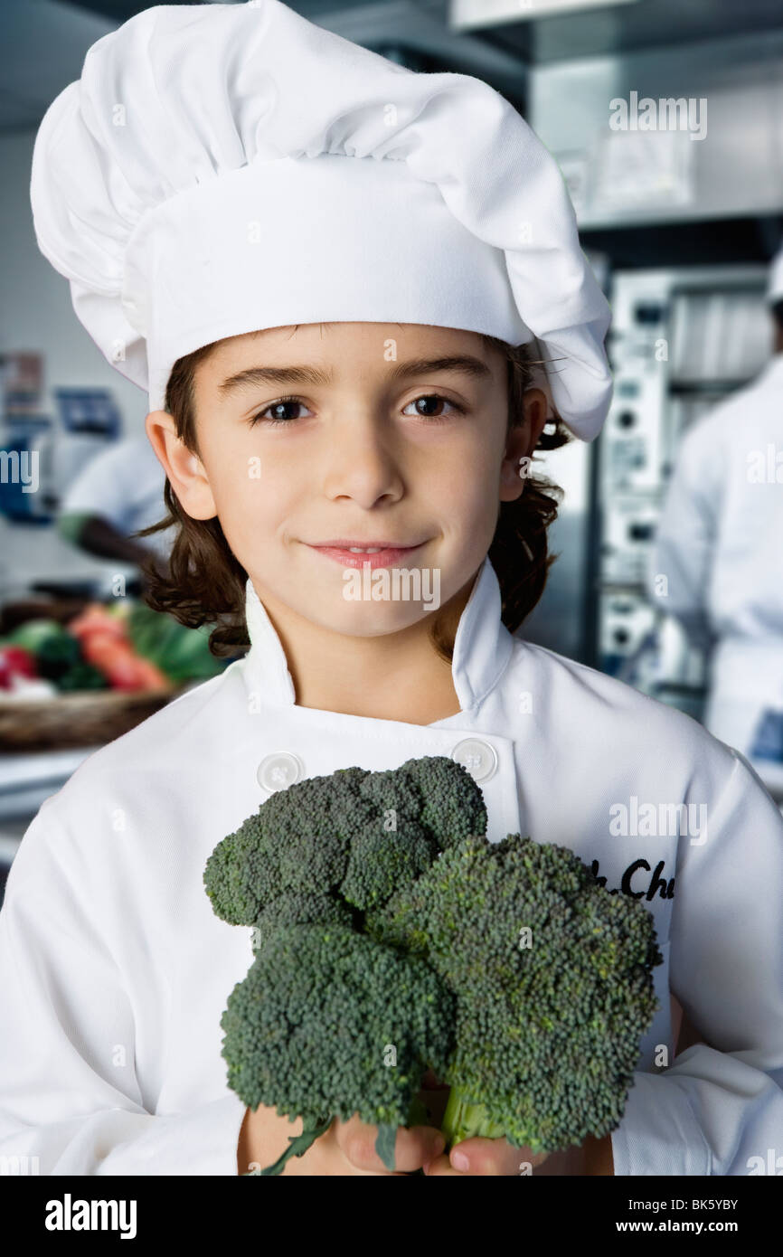 Junge hält einen Brokkoli in der Küche Stockfoto