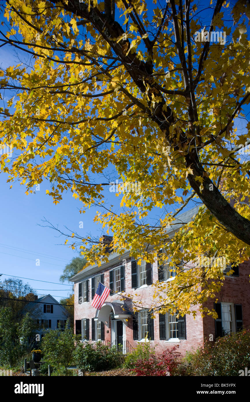 Ein altes Backsteinhaus zeigt eine amerikanische Flagge und umgeben von Herbstlaub in Townshend, Vermont, USA Stockfoto