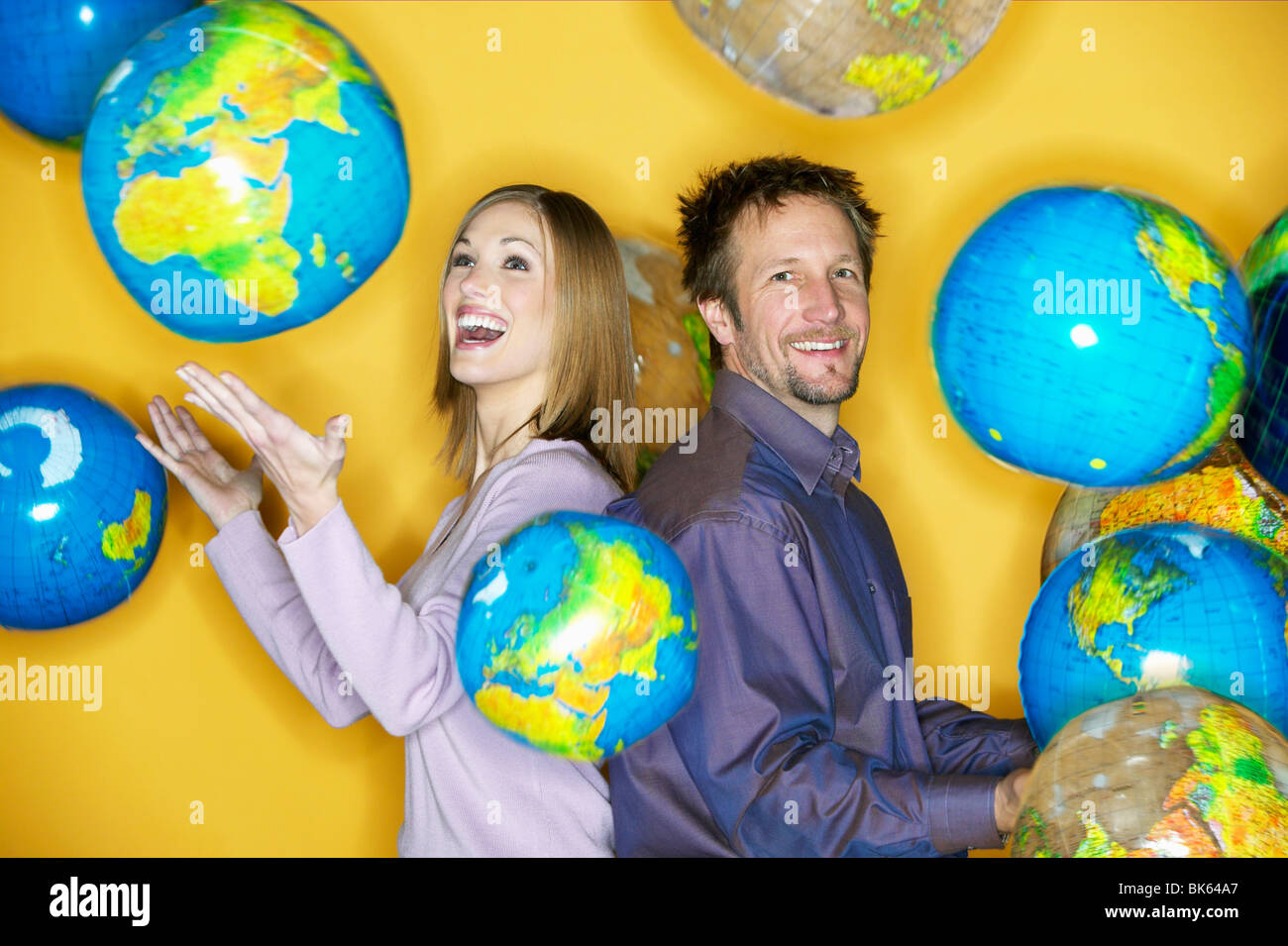 Geschäftsmann und eine Geschäftsfrau posiert mit Globen Stockfoto