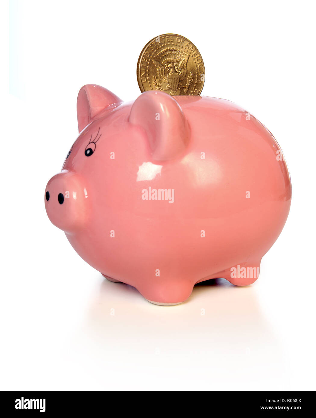 Sparschwein mit Goldmünze auf weißem Hintergrund - Fokus auf Münze Stockfoto