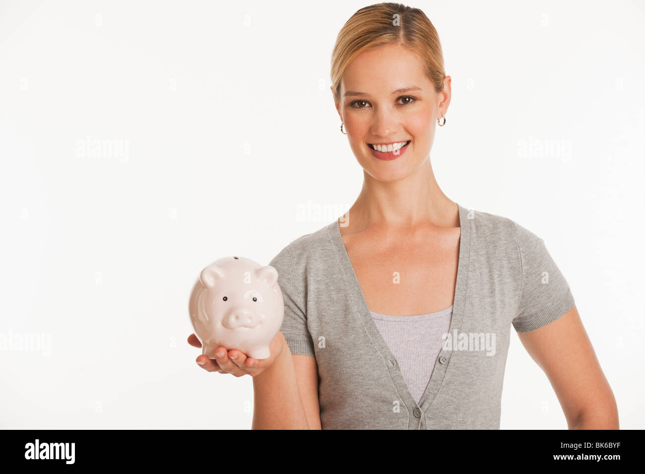 junge Frau hält Sparschwein auf weißem nahtlose Hintergrund Stockfoto