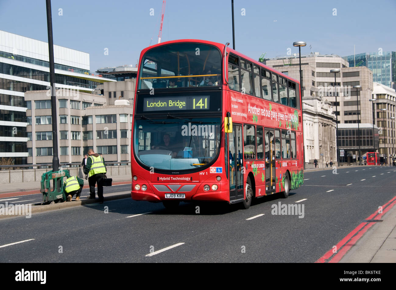Eine Hybrid London Bus überquert London Brücke Richtung London Bridge Station an einem sonnigen Morgen Stockfoto