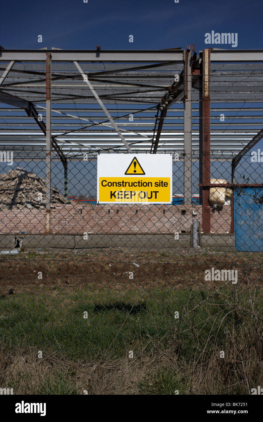 Baustelle fernzuhalten Schild an einem Kettenglied Zaun rund um eine Neuentwicklung, die Baustelle mit alten Fabrik Stockfoto