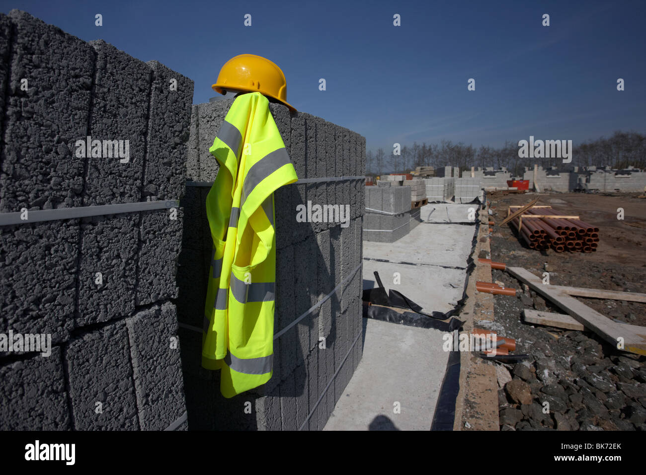 Hard hat und hivis Weste auf einem Haufen von Brise Betonbausteinen auf der Baustelle in Nordirland UK Abwärtstrzessionskonzept Stockfoto