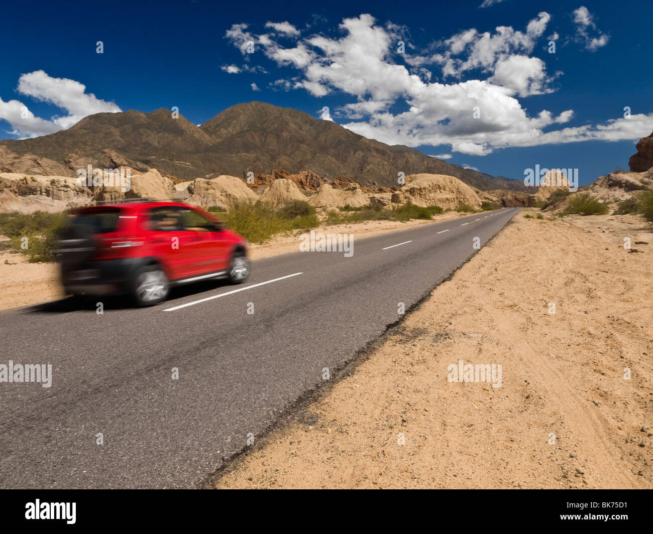 Ein schnelles Auto auf der Straße in einer trockenen und felsigen Landschaft. Stockfoto