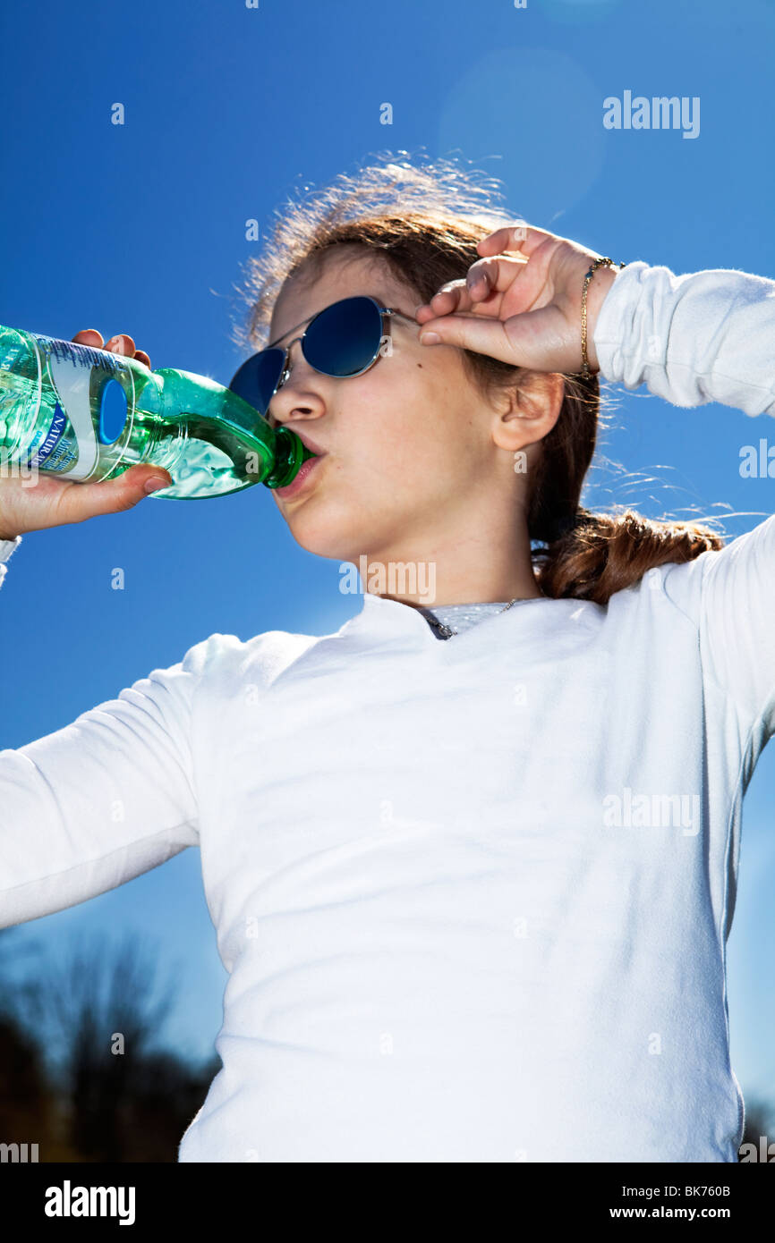Jungen 9 Jahren kaukasische Mädchen trinken Wasser aus einer kleinen Flasche und Rayban Sonnenbrille Stockfoto