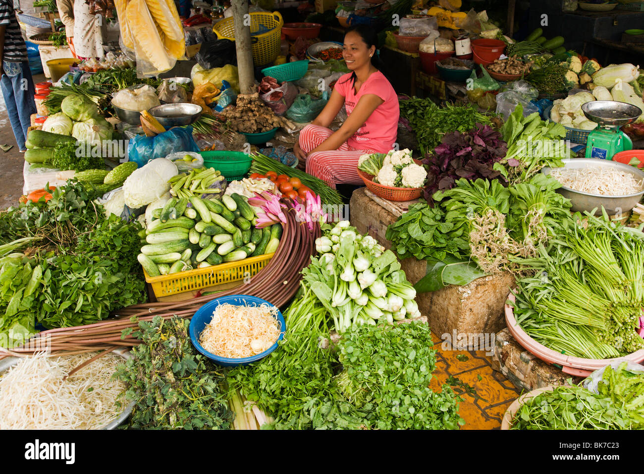 Junge Frau sitzt in ihrem Gemüse Stall auf dem täglichen Markt in der Vietnam Mekong Delta Stadt von Ha Tien Stockfoto