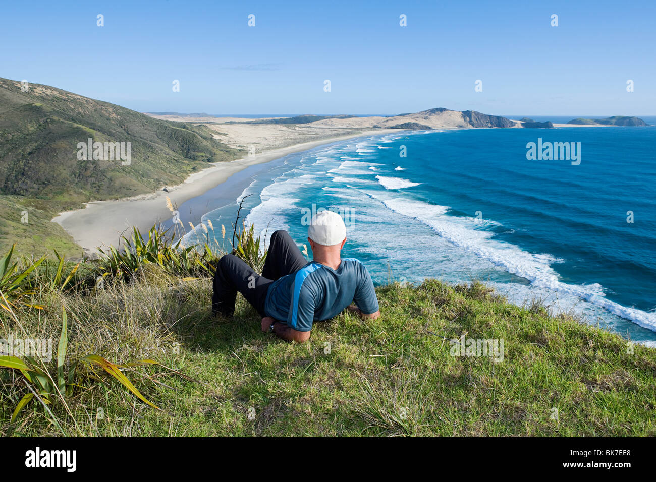 Northland, Cape Lorena, Mann Verlegung auf Rasen, mit Blick auf Strand Stockfoto