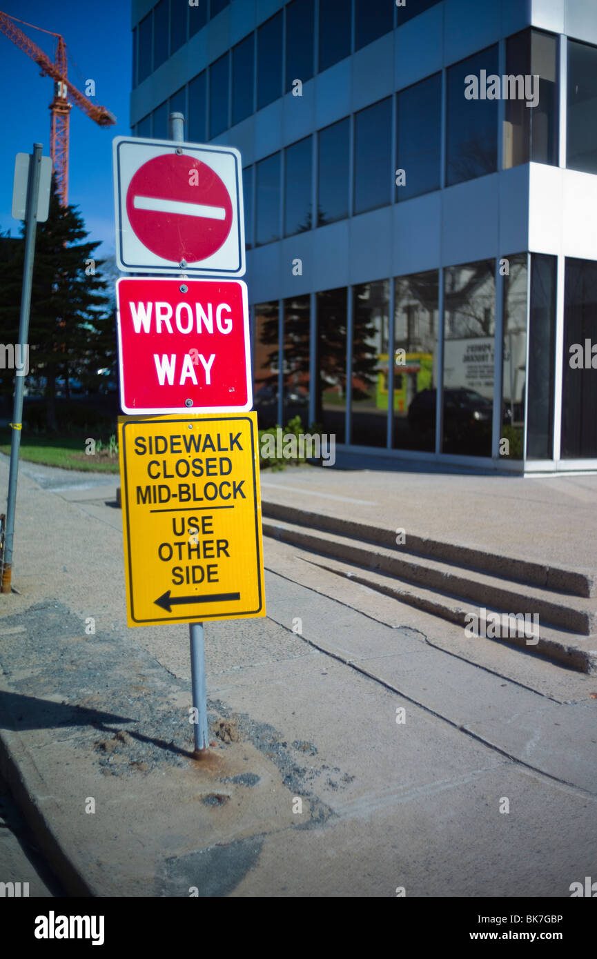 Falsche und Bürgersteig Schilder auf Straße der Innenstadt durch Bürogebäude geschlossen. Baukran im Hintergrund. Stockfoto