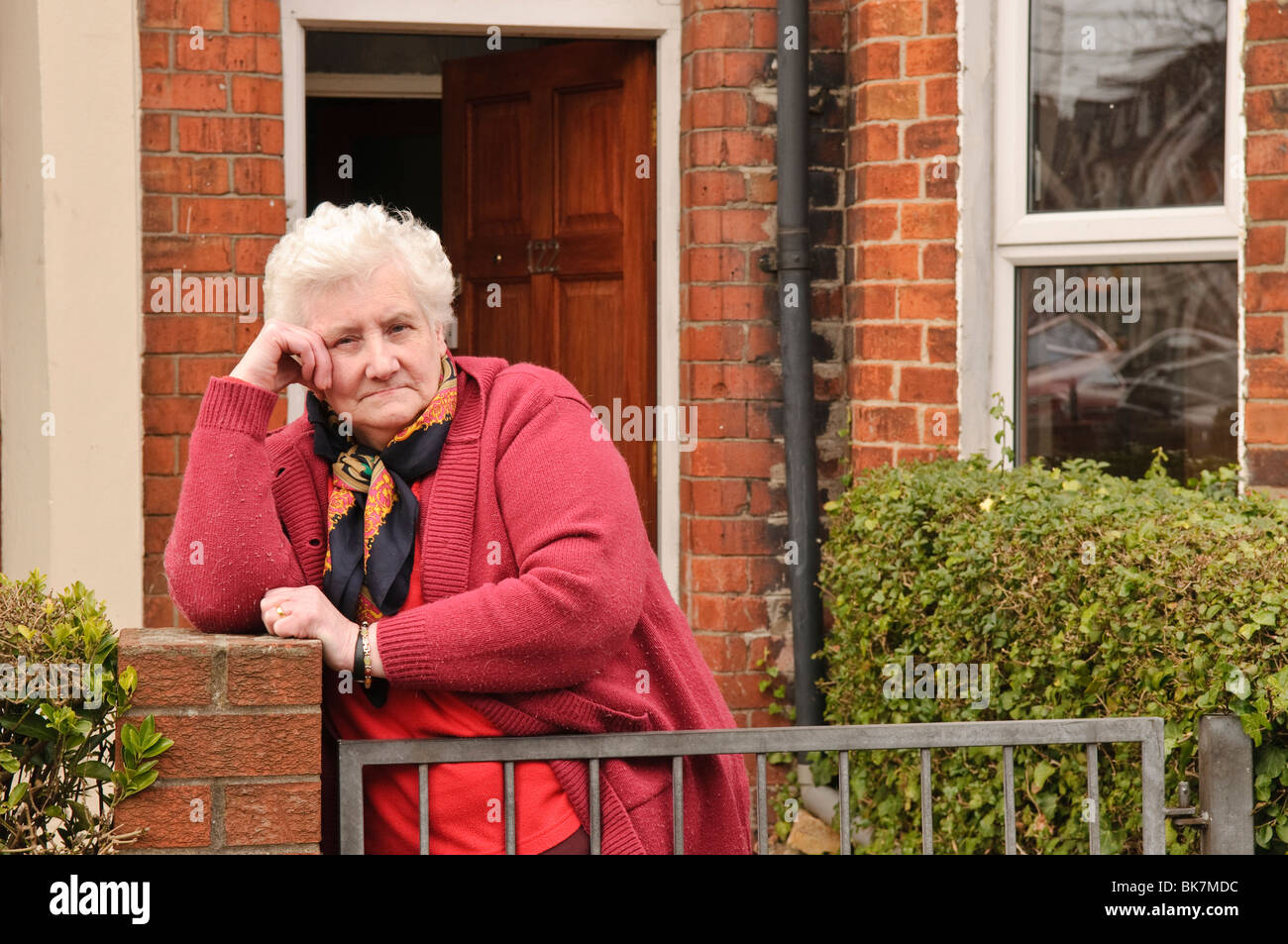 Ältere Frau steht ihr Gartentor, wütend auf Anti-sozialen Aktivitäten, die in ihrer Straße. Stockfoto