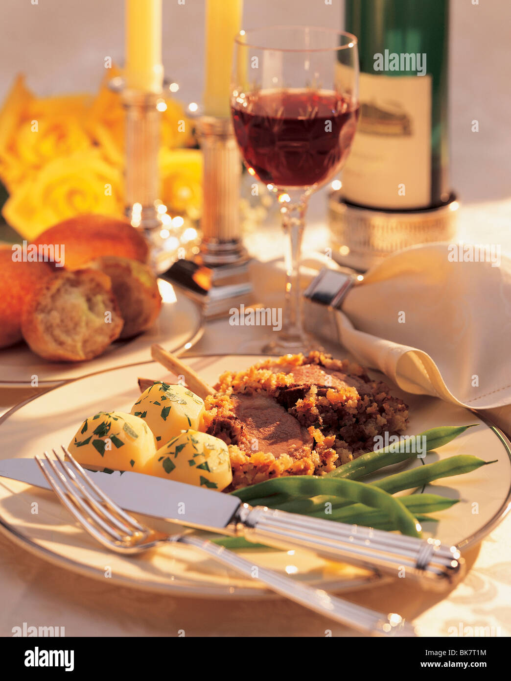 Lammkoteletts, Kartoffeln, grüne Bohnen in einer formalen Platzeinstellung mit Wein. Stockfoto