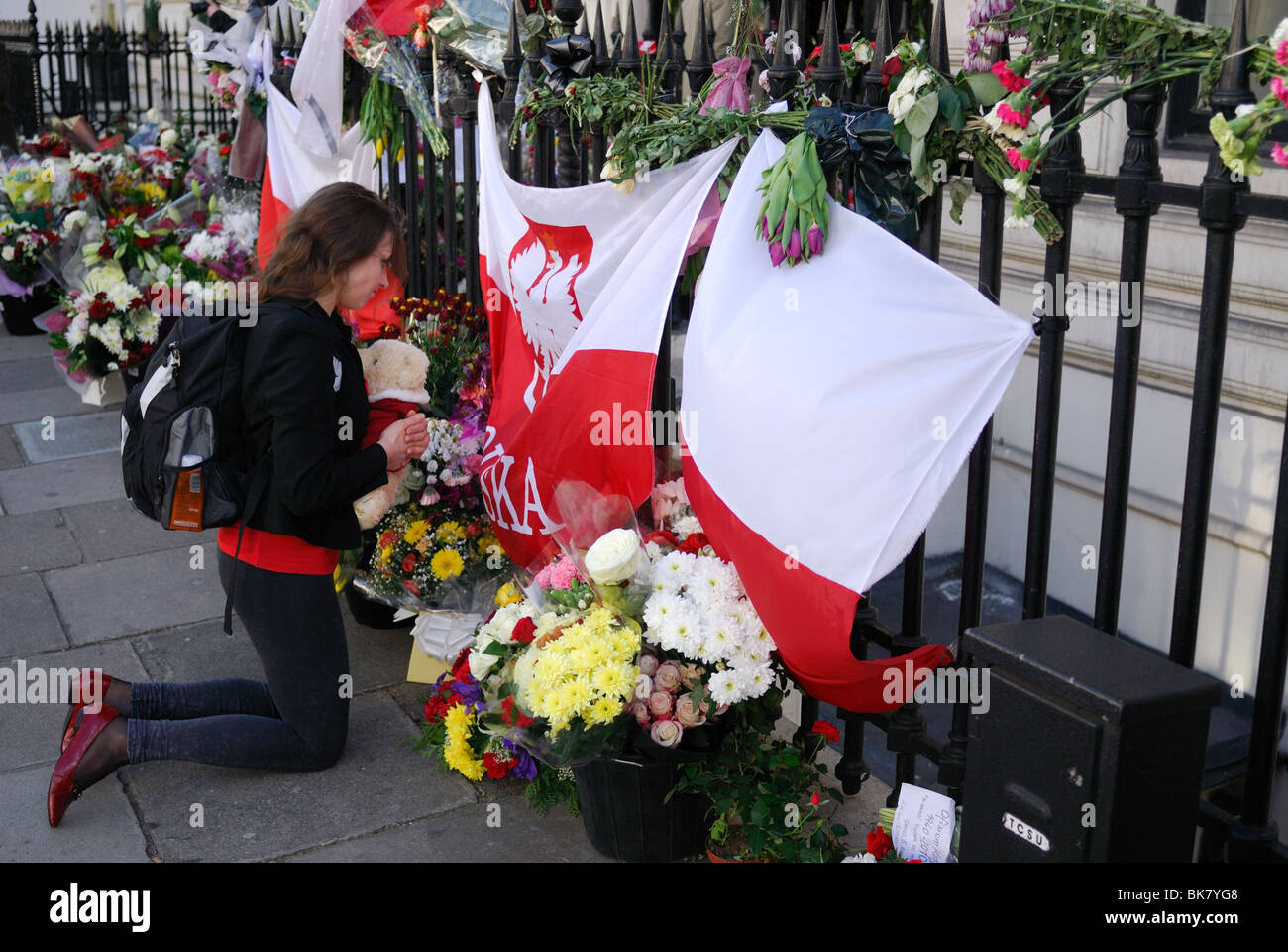 Eine Frau betet mit ihr Teddy Bär vor der polnischen Botschaft in London nach einem Flugzeugabsturz, der Präsidenten getötet Stockfoto