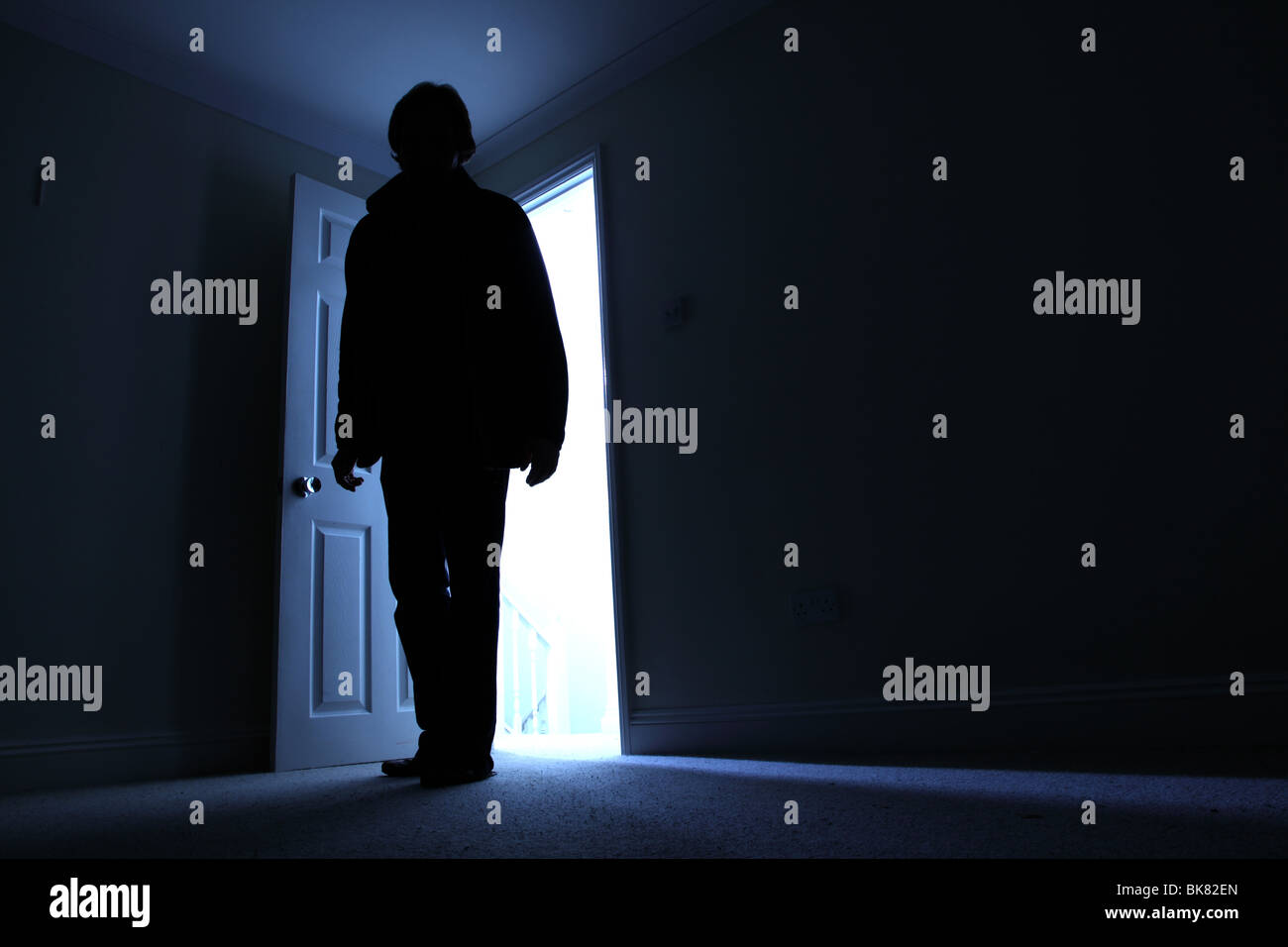 Silhouette eines Mannes in einem dunklen Raum mit einer Welle von Licht hinter Stockfoto