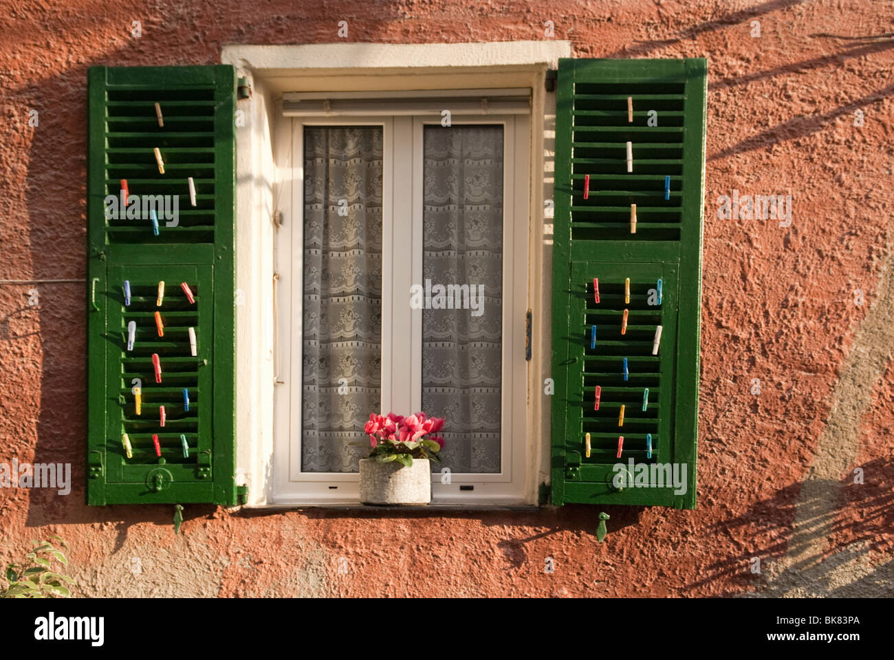 Vorhängen und Fensterläden Fenster an der Mittelmeer Küste mit Blumen und Wäscheklammern im Fenster Stockfoto
