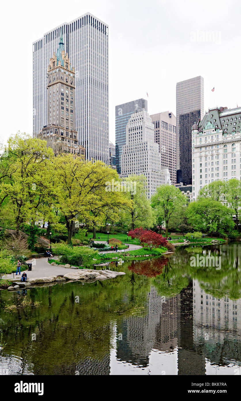 Central Park The Pond Spring Laub New York City // NEW YORK, NY – der Pond im New Yorker Central Park spiegelt die lebhaften Farben des Frühlings wider, mit blühenden Bäumen und frischem Laub rund um das ruhige Wasser. Im Hintergrund erhebt sich die berühmte Skyline von Manhattan über dem Park und schafft einen eindrucksvollen Kontrast zwischen der natürlichen Oase und der urbanen Landschaft von Midtown. Stockfoto