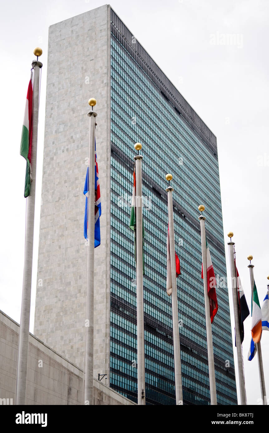 Flaggen des Hauptsitzes der Vereinten Nationen New York City // NEW YORK, Vereinigte Staaten — vor dem ikonischen UN-Sekretariatsgebäude, dem Hauptsitz des Hauptsitzes der Vereinten Nationen in New York City, flattern bunte Flaggen, die die mitgliedsstaaten der Vereinten Nationen repräsentieren. Diese eindrucksvolle Darstellung internationaler Einheit steht vor dem Hintergrund der schlanken, modernistischen Architektur, die zu einem Symbol für globale Diplomatie und Zusammenarbeit geworden ist. Stockfoto
