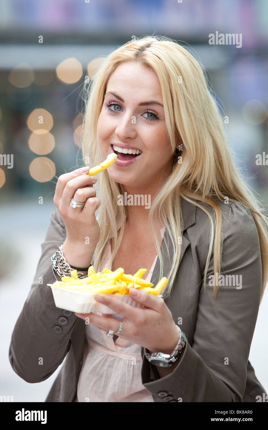 Schöne junge blonde Mädchen essen Pommes frites Stockfoto